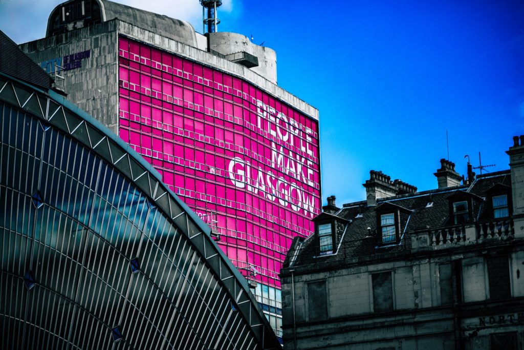 A view of building in Glasgow, Scotland with a large mural with the words "People Make Glasgow".