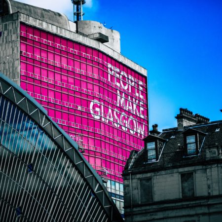 A view of building in Glasgow, Scotland with a large mural with the words "People Make Glasgow".