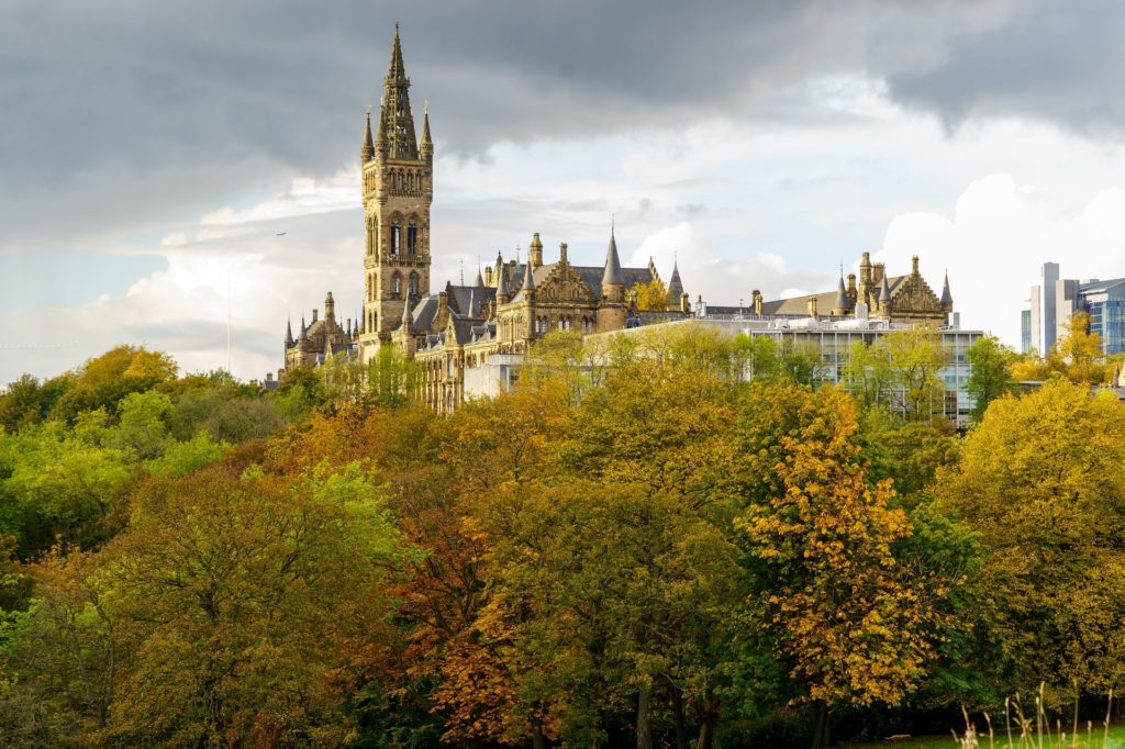 A view of the clock tower in Glasgow, Scotland. Vegetation with fall colors is in the foreground.